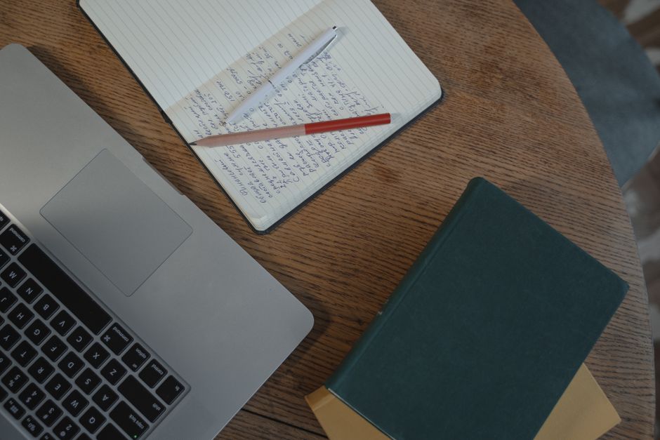 A clean, organized workspace featuring a laptop, notebooks, and pens on a wooden table, perfect for productivity.